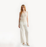 Woman wearing a light pink sleeveless top and pants on a white background, front-view