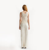 Woman wearing a light pink sleeveless top and pants on a white background, rear-view