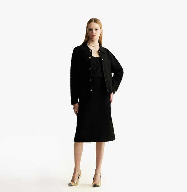 Black A line midi skirt with embossed jacquard texture built in side pockets and structured waist hem details.front-view.