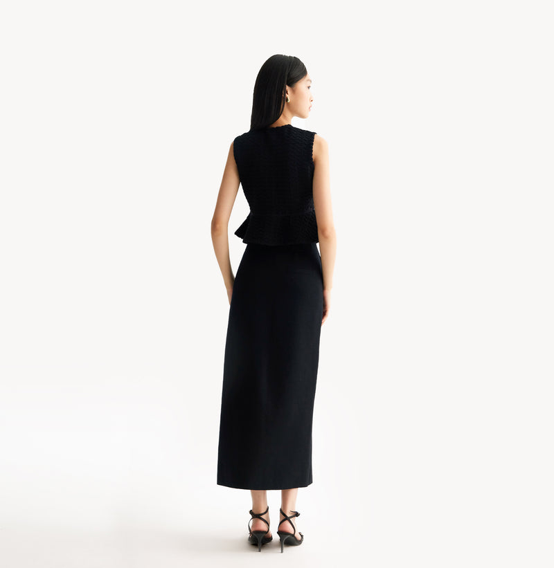 Black womens fitted vest in wool blend stretch fabric with cinched waist flared hem and seamless edge trim. rear-view.