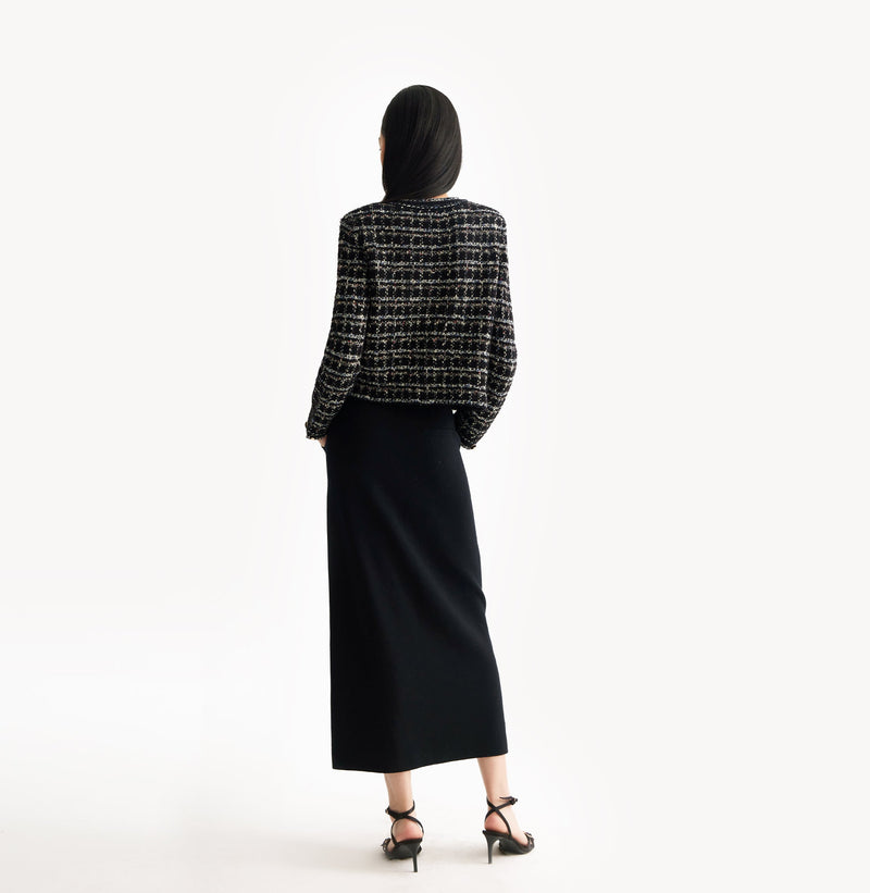 Black female tweed jacket with crewneck, four front pockets, velvet metal logo buttons, and buttoned sleeve vents. 