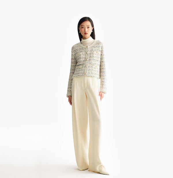 White female tweed jacket with crewneck, four front pockets, velvet metal logo buttons, and buttoned sleeve vents. front-view.