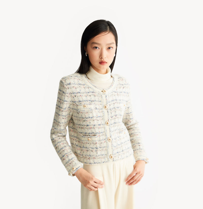 White female tweed jacket with crewneck, four front pockets, velvet metal logo buttons, and buttoned sleeve vents. left-view.