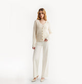 Woman wearing a cream cardigan and pants on a white background, front-view