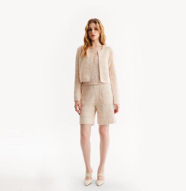 Woman wearing a pink cardigan on a white background, front-view