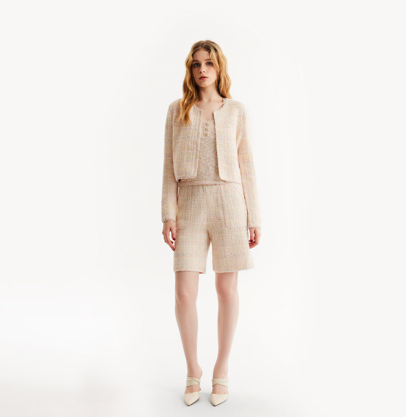 Woman wearing a pink cardigan on a white background, front-view