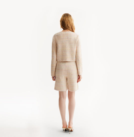 Woman wearing a pink cardigan on a white background, rear-view