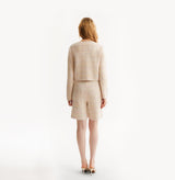 Woman wearing a pink cardigan on a white background, rear-view