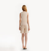 Woman wearing a pink crewneck vest on a white background, rear-view