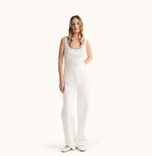 Woman wearing a white sleeveless top and pants on a white background, front-view