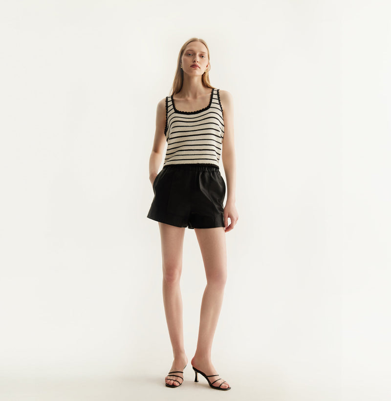 Black sheepskin shorts with relaxed pleated design and elastic waistband.