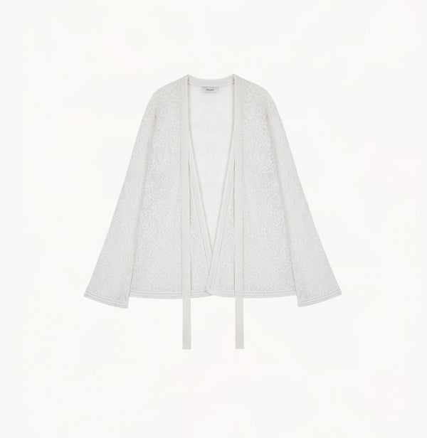 White relaxed fit lace cardigan with shimmering sequin yarn, pointelle trim, and ribbon neckline. 