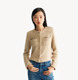 Beige ladies cropped boucle jacket in cashmere blend with shoulder padding, folded edges, and double-layered pocket flaps. 