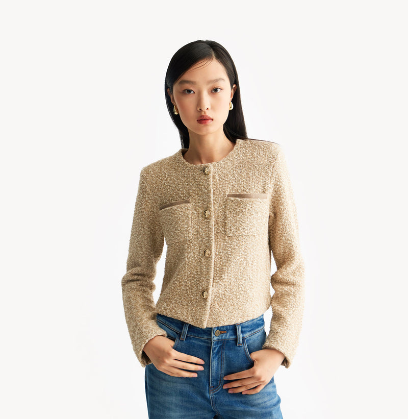 Beige ladies cropped boucle jacket in cashmere blend with shoulder padding, folded edges, and double-layered pocket flaps. 