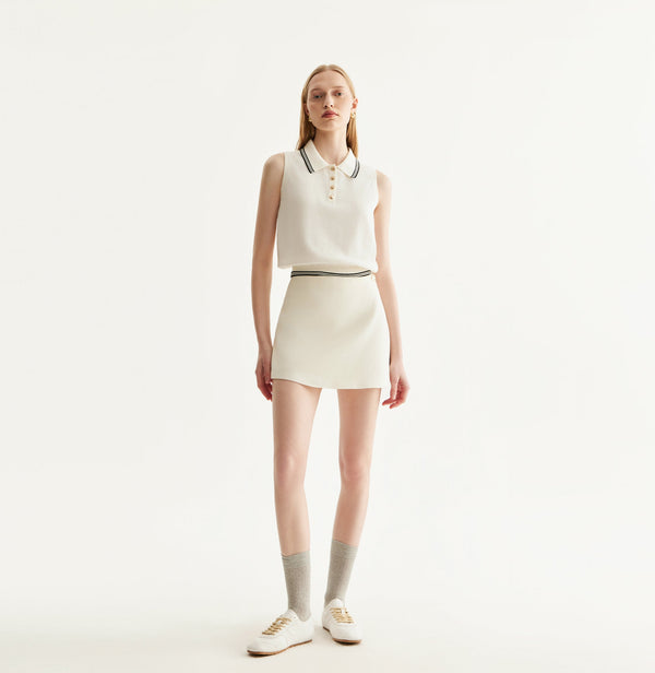 White cotton skort with fitted miniskirt design, built-in shorts, and front flap decorative metal buttons. front-view
