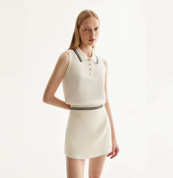 White cotton skort with fitted miniskirt design, built-in shorts, and front flap decorative metal buttons. left-view